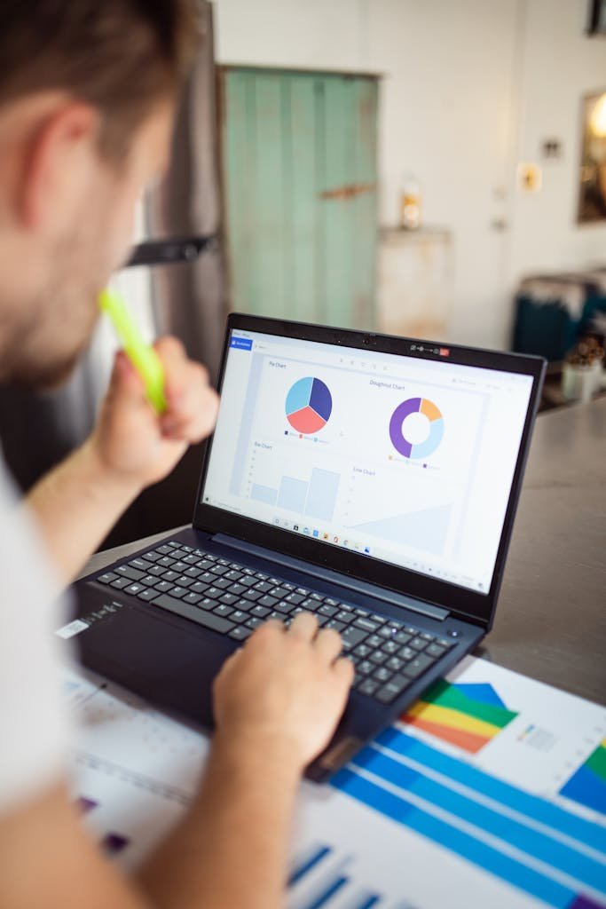 Focused adult analyzing charts and graphs on a laptop for business insights.